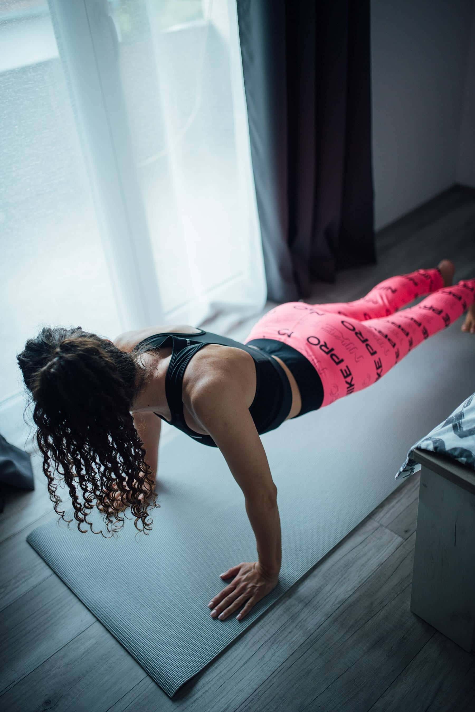 A woman exercising on a mat at home by a window in morning light